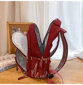 Detailed view of large capacity burgundy school backpack with multiple zipper compartments and embroidery.