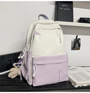 Detail view of the white and purple colorblock casual backpack with cute bear pendant accessory.