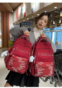 Detail shot of large capacity red backpack with cute embroidery and pendants in store setting.
