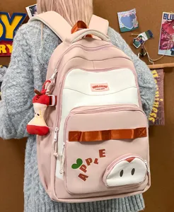 Vista detallada de elegante mochila rosa de gran capacidad con bonito colgante de manzana.