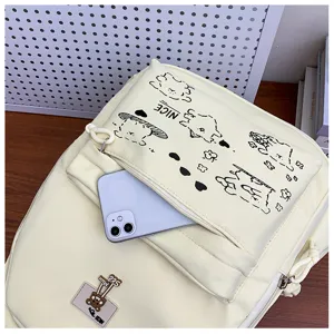 Detail shot of fresh canvas backpack with cute cartoon prints and front pocket holding phone.