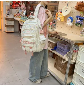 Large capacity canvas student school backpack with cute graffiti design and plush dog pendant.
