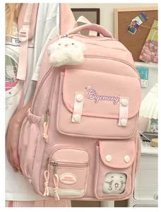 Pink backpack detail showing multi-pocket design, cute doll pendant and clear window pocket.