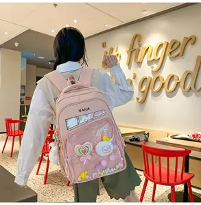 Mochila escolar rosa de estilo japonés con bolsillo frontal transparente y colgantes bonitos.