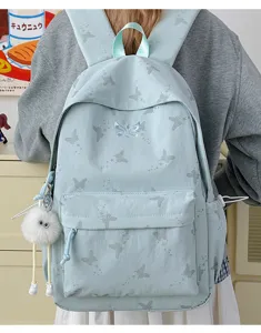 Detail view of light blue student backpack with cute butterfly pattern and plush keychain.