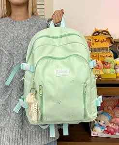 Light green cute student backpack detail showing bow embroidery and multiple compartments.