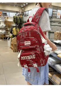 Large capacity red school backpack for students with cute plush pendant and stylish letter design.