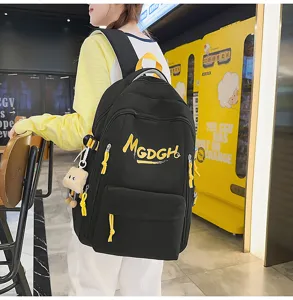 Detailed view of casual black student backpack with yellow straps and cute pendant.