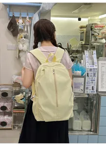Close-up showing the light yellow casual backpack with cute embroidered bow details and straps.