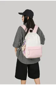 Casual two-tone canvas backpack detail showcasing pink and white color block with cute pendant.