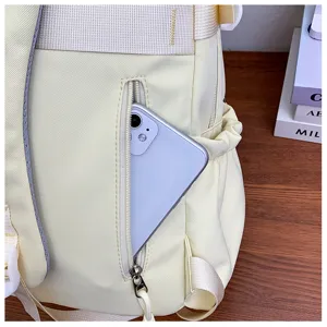 Detailed view of the light yellow casual backpack featuring a front zipper pocket and durable straps.