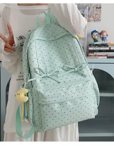 Detailed view of the cute light green polka dot school backpack with sweet bows and a pendant.