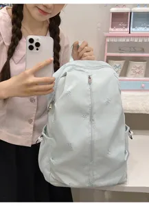 Detailed view of light blue backpack with cute embroidered bows and practical front zipper pocket.