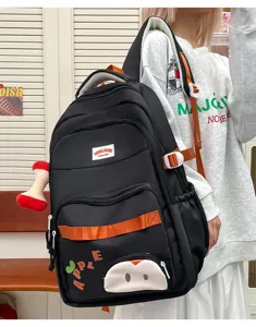 Detalle de mochila de viaje negra informal, gran bolsa escolar con correas naranjas y manzana.