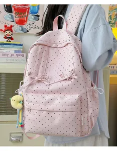 Cute pink polka dot backpack detail showcasing lovely bow accents and practical side pockets.