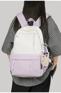 Details of the stylish contrast color backpack, featuring a cute bear pendant and practical pockets.