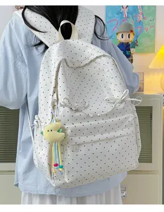 Detail view of cute polka dot backpack with sweet bows and plush pendant in cozy room setting.
