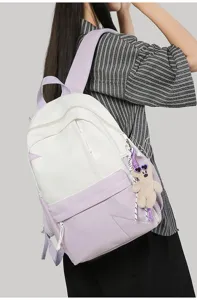 Casual minimalist dual-tone backpack detail showing contrast color design and cute bear pendant.