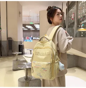 Detailed view of the light yellow casual backpack with front pocket and plush charm accessory.