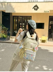 Detail view of casual canvas backpack with checkerboard pocket and cute pendant for daily commute.