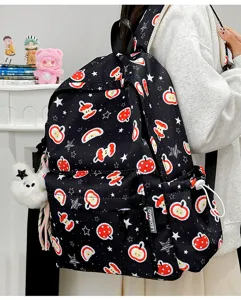 Detailed view of cute apple print black backpack with star patterns and plush charm for daily use.