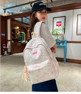 Pink textured casual school backpack detail view with cute pendant and fashionable tassel charm.