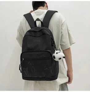 Detail view of the stylish black canvas backpack with bamboo pattern and cute panda keychain.