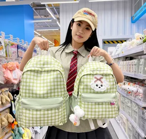 Detailed view of the cute green plaid student school backpack with a fluffy plush dog charm.