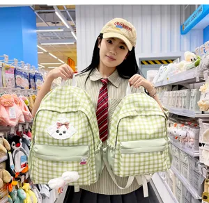 Green plaid student backpack detail view with cute dog embroidery and fluffy pendant for school