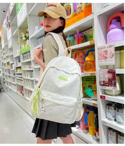 Detail view of the stylish white textured backpack with a cute bear pendant in a retail store.