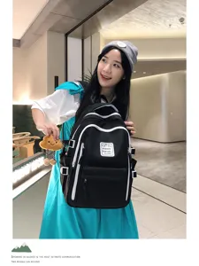 Detail view of a Japanese style black and white color block student backpack worn by model.