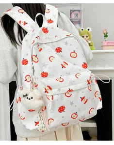 Cute white apple print school backpack with plush pendant, stylish student daypack.