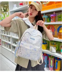 Backpack detail view showing floral pattern, blue tassel, and cute bear pendant design.