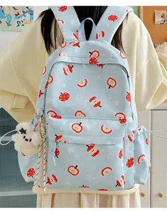Detail shot of cute cartoon apple print blue backpack with plush bear pendant for daily use.