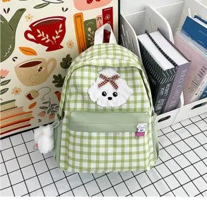 Detailed close-up of the charming green plaid student backpack with cute puppy plush patch and bow.
