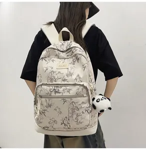 Detailed view of lightweight beige backpack with bamboo pattern and cute panda pendant.