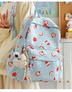 Cute blue apple print backpack with plush dog charm for daily school and casual travel.