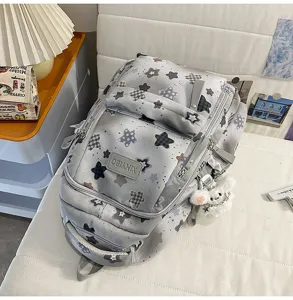 Detail view of casual star printed grey school backpack with multiple pockets and plush pendant.