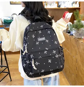 Black casual school backpack with cute white bows and dots for daily student travel use.
