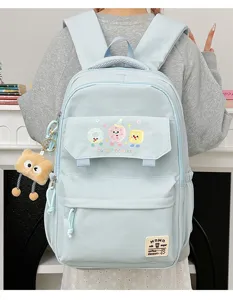 Detailed view of light blue student backpack with cute cookie print and plush pendant.