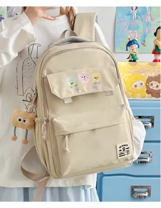 Detailed view of casual beige canvas backpack with cute cartoon patches and front multi-pocket.