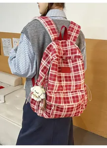 Detail shot of the retro red plaid backpack showcasing compartments and cute plush pendant.