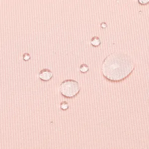 Dettaglio del tessuto impermeabile rosa dello zaino scolastico con forte idrorepellenza.