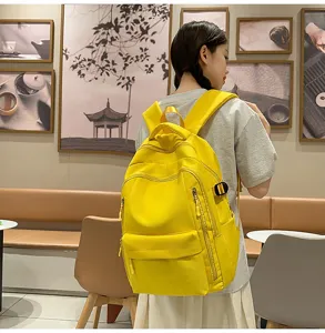 Vue détaillée du sac à dos jaune décontracté porté par un modèle dans un café chaleureux.