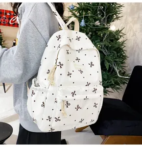 White canvas bow pattern backpack, casual school bookbag featuring front pocket and large capacity.