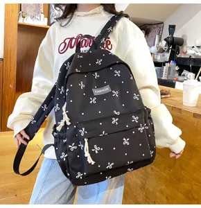 Detail view of black canvas school backpack with white bows and dots, casual daily use.