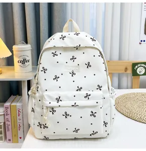 White casual backpack with black bow and dot print, stylish school bag for students daily use.