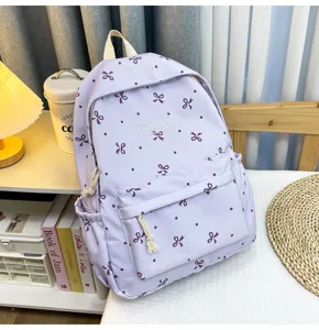 Detailed view of the stylish purple school backpack with cute bow patterns and front pocket.