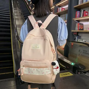 Pink canvas school backpack with floral front pocket and cute puppy pendant for daily commuting.