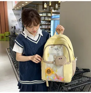 Close-up view of the cute yellow ita bag with transparent pocket and playful plush charms.